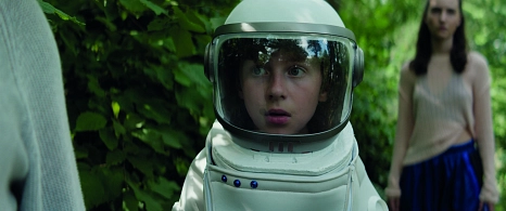 Im Vordergrund ist ein Junge zu sehen, der einen Astronautenanzug trägt. Im Hintergrund steht ein Mädchen. © Farbfilm Verleih