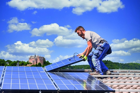 Zwei Männer installieren eine Photovoltaikanlage auf einem Dach. Im Hintergrund das Marburger Schloss. © Adobe Stock © mmphoto, Adobe Stock © Circumnavigation, Layout: mr//media GmbH