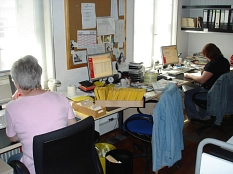 Zwei Mitarbeiterinnen sitzen an den Schreibtischen im Büro und bearbeiten Rechnungen.