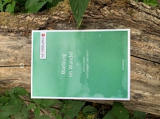 Auf einem breiten Ast, umgeben von grünen Blättern, liegt die Broschüre Marburg im Wandel © Universitätsstadt Marburg, Jochen Friedrich