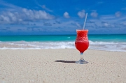 Strand mit blauem Himmel und einem roten Drink