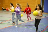 Lachende Mädchen laufen mit Basketbällen durch eine Sporthalle. © Simone Batz, Stadt Marburg